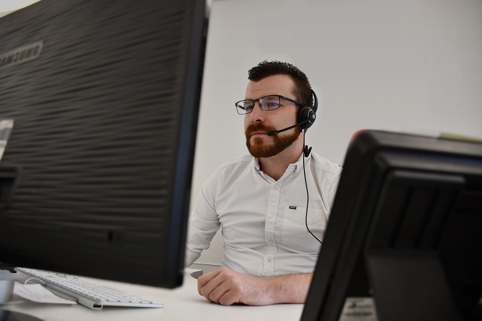 A man wearing a headset, working on a computer