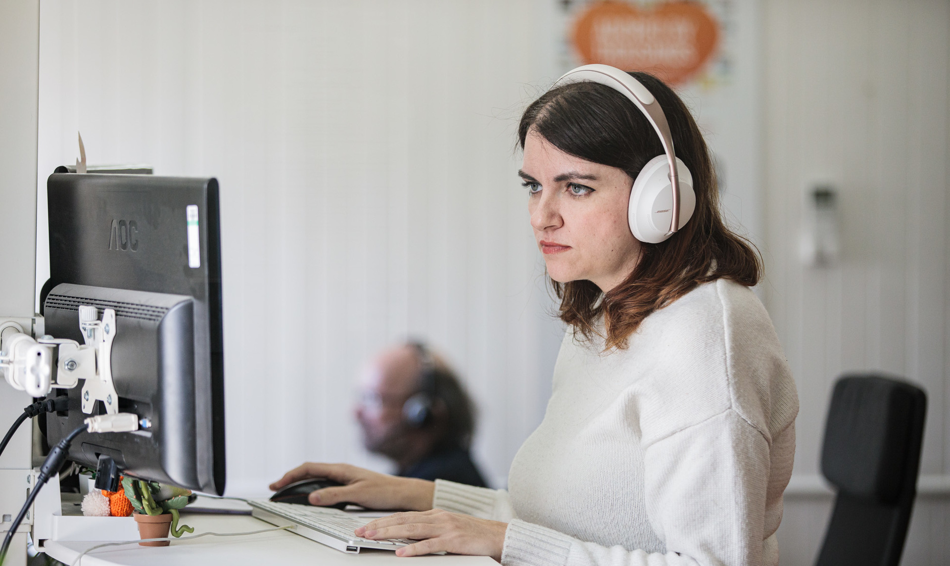 A lady with headphones on, stood at her desk designing a new website