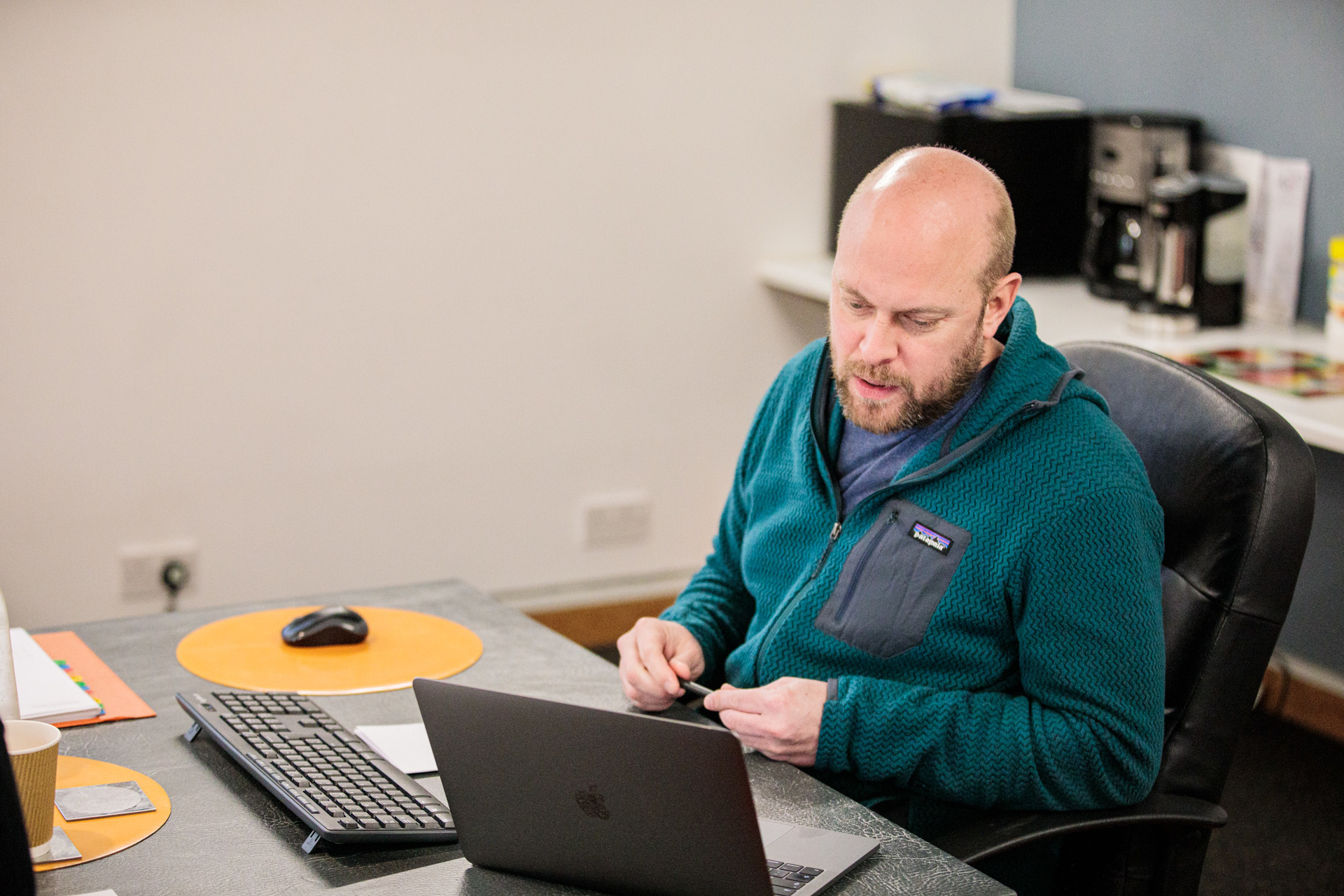 A digital marketing manager sat at his desk, looking at a laptop